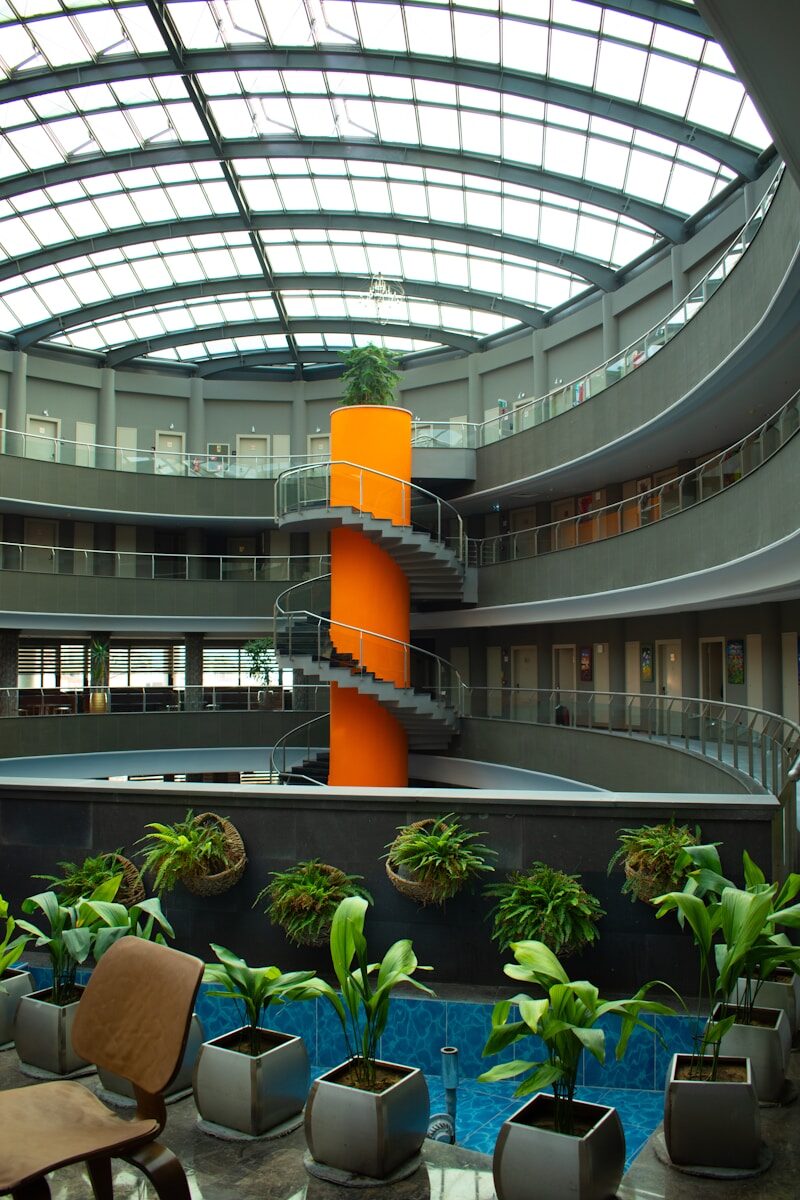 An atrium with spiral staircase and indoor plants.