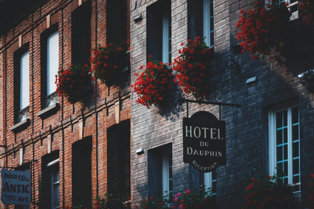 Elegant hotel facade featuring brickwork and vibrant flower boxes in a quaint European setting.