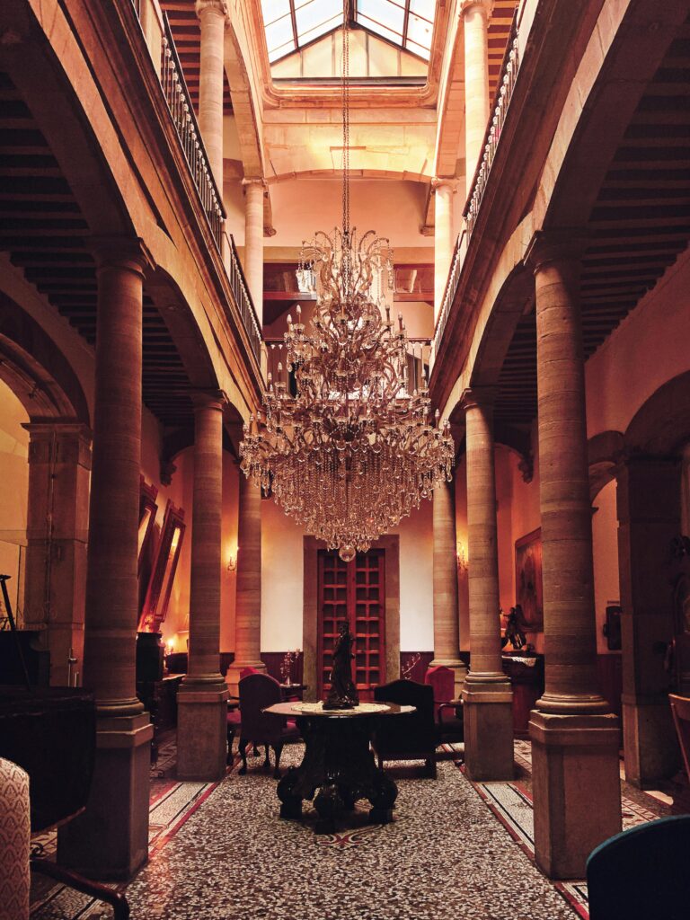 A grand chandelier lights up the elegant hotel atrium in Guanajuato, Mexico, exuding luxury and architectural charm.