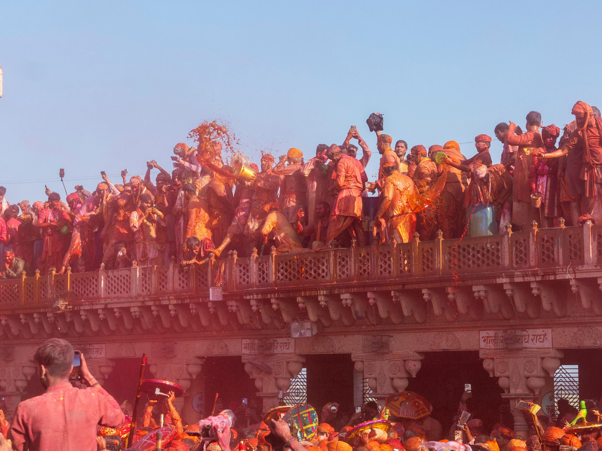 Crowds celebrate Holi with vibrant colors at Nandgaon temple in India.