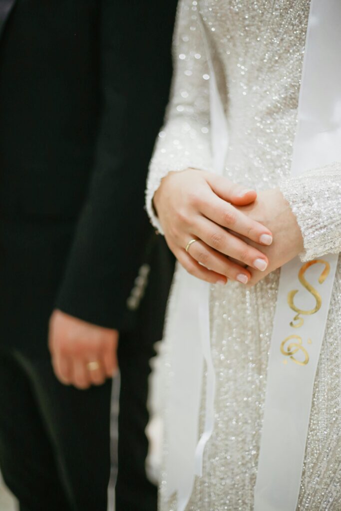 Bride and groom holding hands in a close-up during a wedding ceremony.