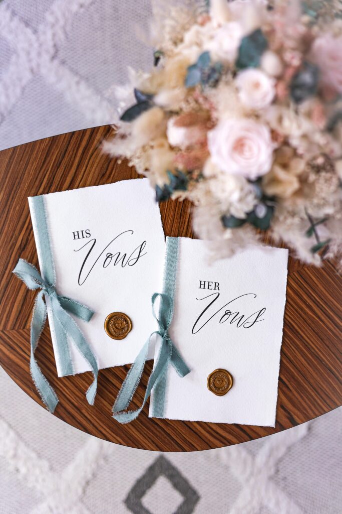 Beautifully styled his and her vow books with a floral bouquet on a wooden table, perfect for weddings.
