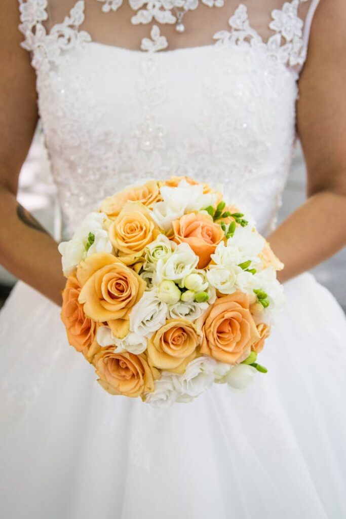 A bride holding an elegant bouquet of peach and white roses, ready for the wedding ceremony.