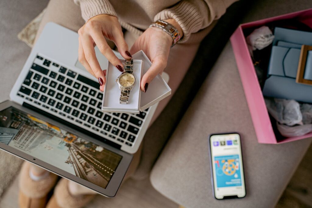 Woman unboxing a watch while online shopping using a laptop and smartphone. Perfect for lifestyle and technology themes.