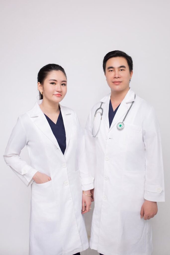 Portrait of male and female healthcare professionals in studio setting, wearing white coats.