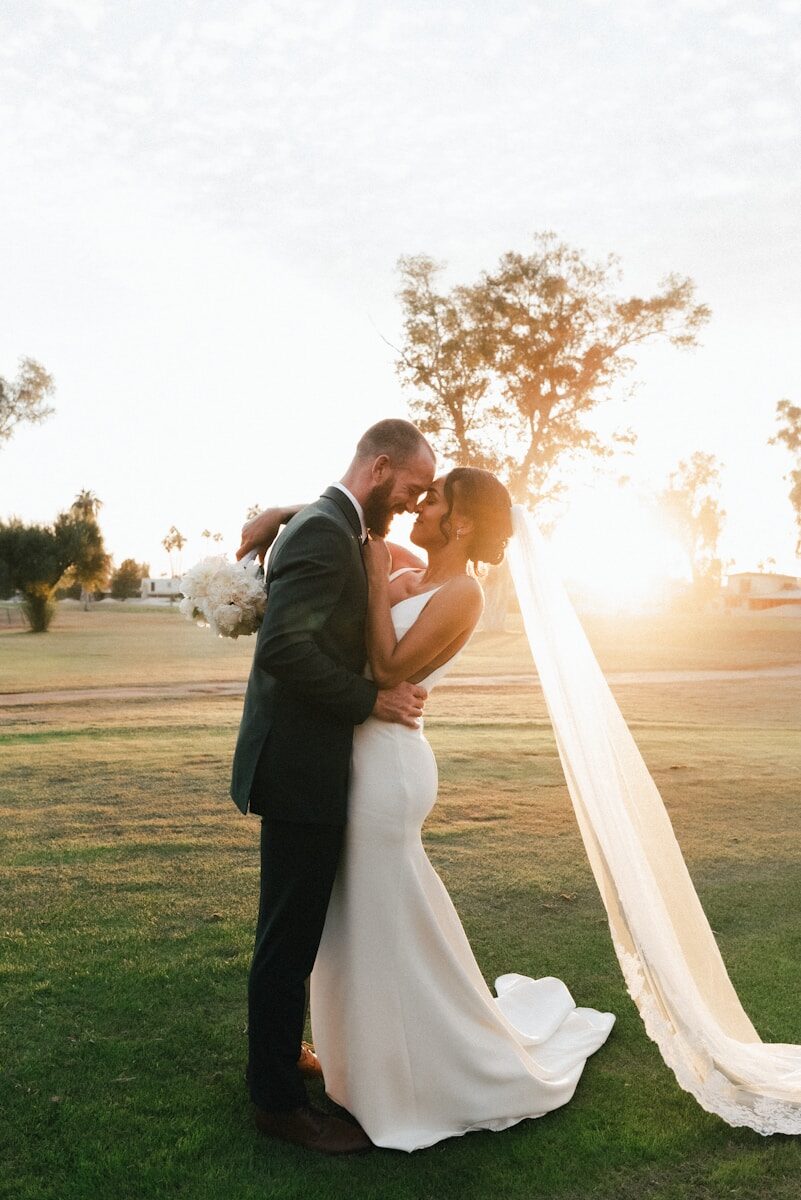man and woman kissing on green grass field during sunset